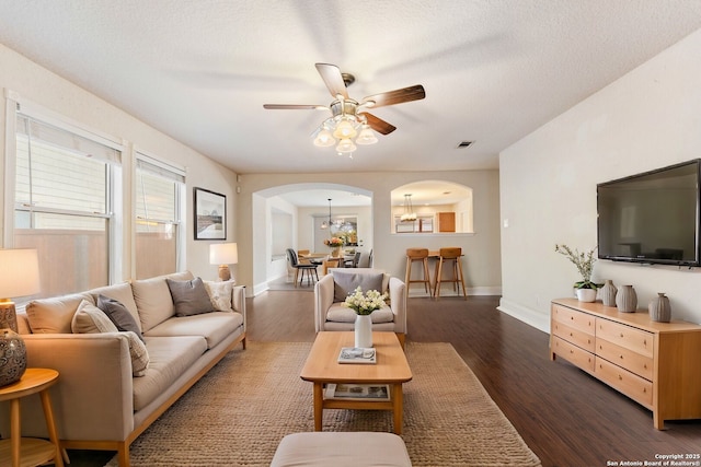 living room featuring a textured ceiling, dark hardwood / wood-style flooring, and ceiling fan with notable chandelier