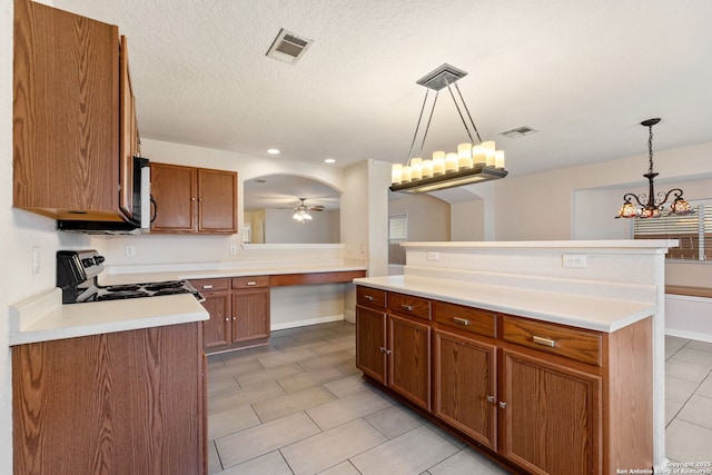 kitchen featuring pendant lighting, ceiling fan with notable chandelier, a kitchen island, and stove