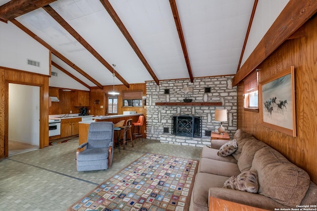 living room featuring beam ceiling, sink, high vaulted ceiling, wood walls, and a fireplace