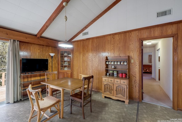 dining space with beam ceiling, wood walls, and high vaulted ceiling