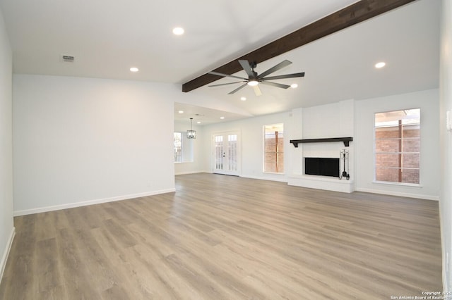 unfurnished living room with a large fireplace, vaulted ceiling with beams, ceiling fan, and light hardwood / wood-style flooring