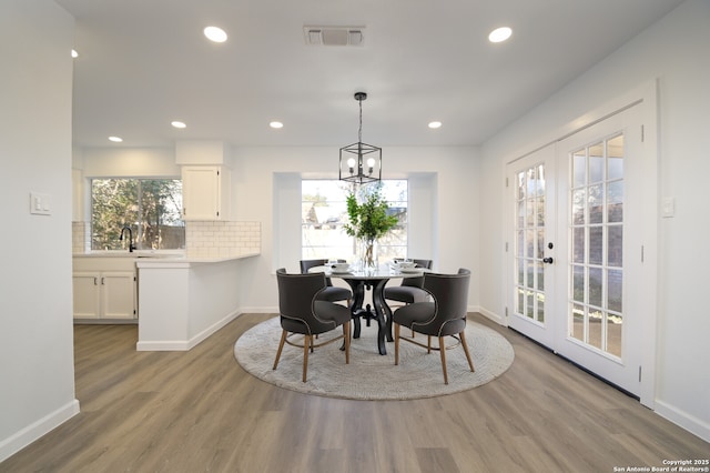 dining space featuring a chandelier, sink, light hardwood / wood-style floors, and french doors