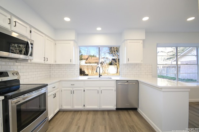 kitchen featuring kitchen peninsula, white cabinetry, sink, and appliances with stainless steel finishes