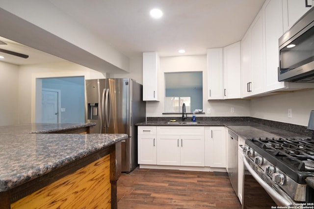 kitchen featuring sink, white cabinetry, stainless steel appliances, and dark stone counters