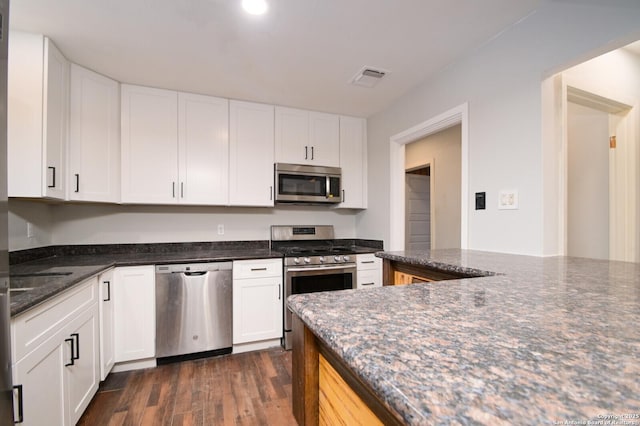 kitchen featuring dark stone counters, white cabinetry, dark hardwood / wood-style flooring, and stainless steel appliances