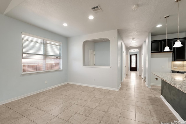 spare room featuring light tile patterned floors and a textured ceiling