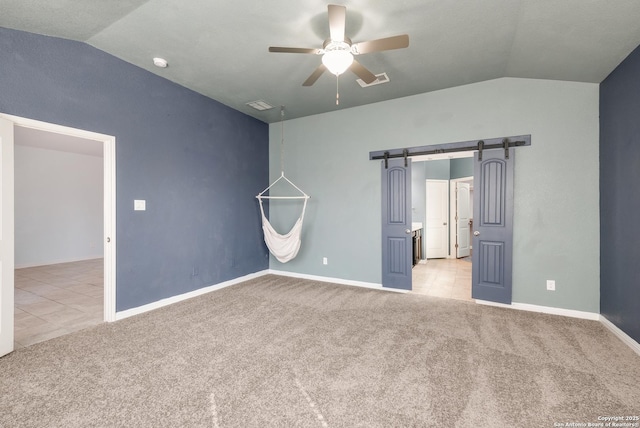 unfurnished bedroom with a barn door, light colored carpet, ceiling fan, and lofted ceiling