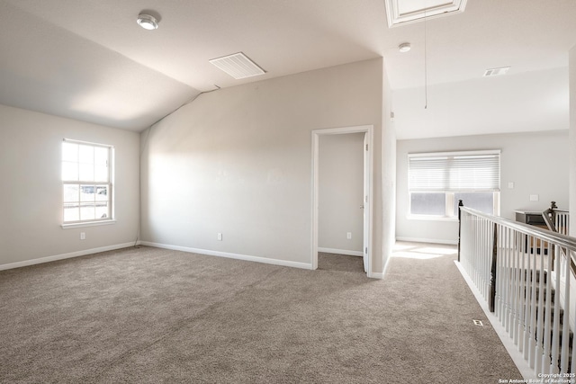 carpeted spare room with a healthy amount of sunlight and lofted ceiling