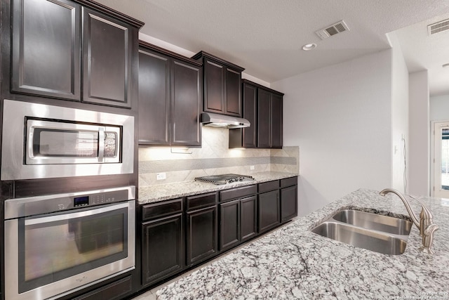 kitchen with decorative backsplash, dark brown cabinetry, sink, and appliances with stainless steel finishes