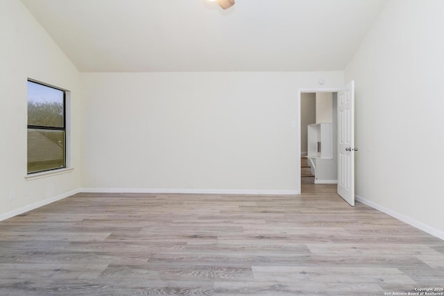 unfurnished room with light wood-type flooring and vaulted ceiling