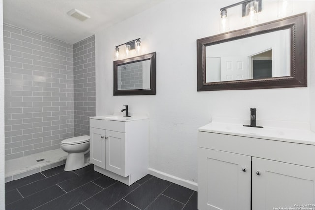 bathroom with tile patterned flooring, a tile shower, vanity, and toilet