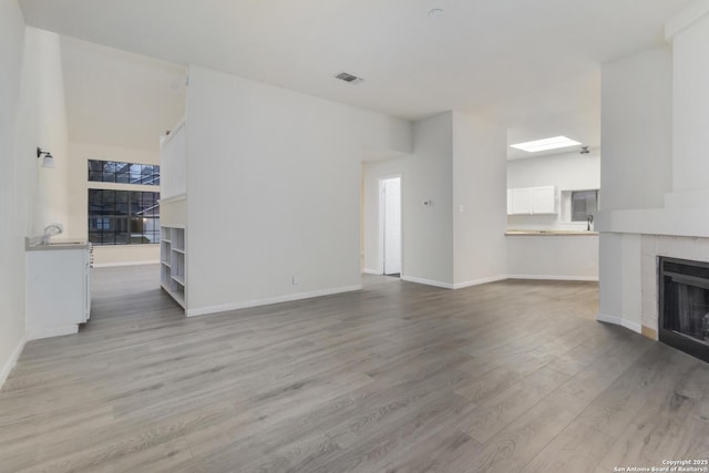 living room with a tile fireplace and light hardwood / wood-style floors