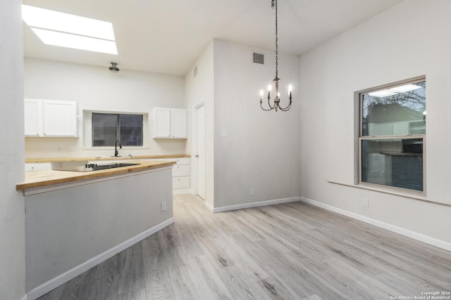 kitchen featuring wood counters, light hardwood / wood-style flooring, white cabinetry, and hanging light fixtures