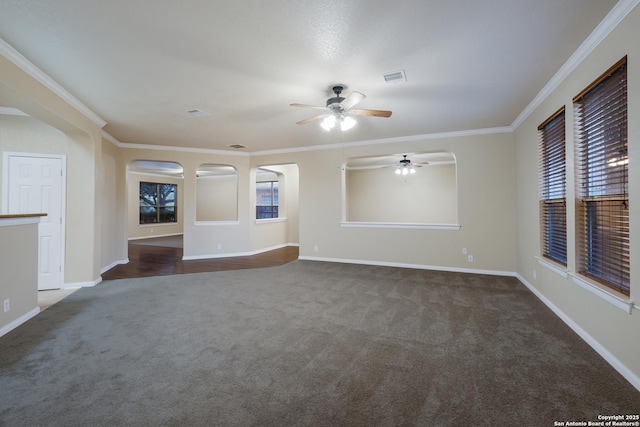 unfurnished living room with dark carpet, ceiling fan, and crown molding