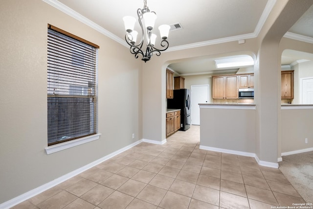 kitchen with black fridge, crown molding, decorative light fixtures, a notable chandelier, and light tile patterned flooring