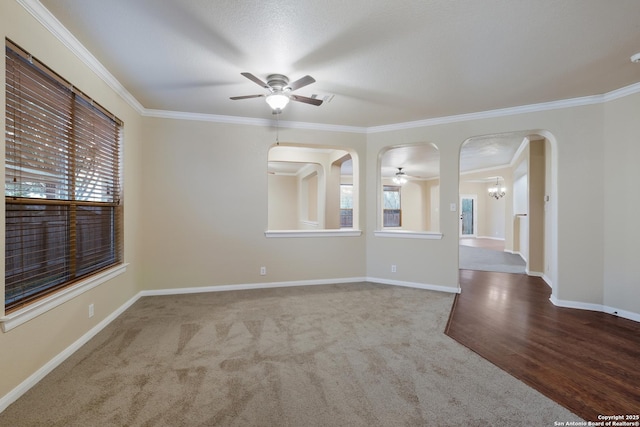 spare room with carpet, ceiling fan with notable chandelier, and ornamental molding