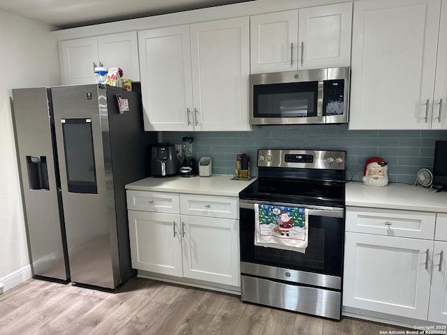 kitchen with decorative backsplash, white cabinetry, light hardwood / wood-style flooring, and stainless steel appliances