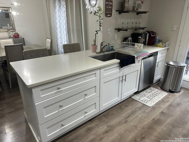 kitchen with white cabinetry, stainless steel dishwasher, hardwood / wood-style flooring, and sink