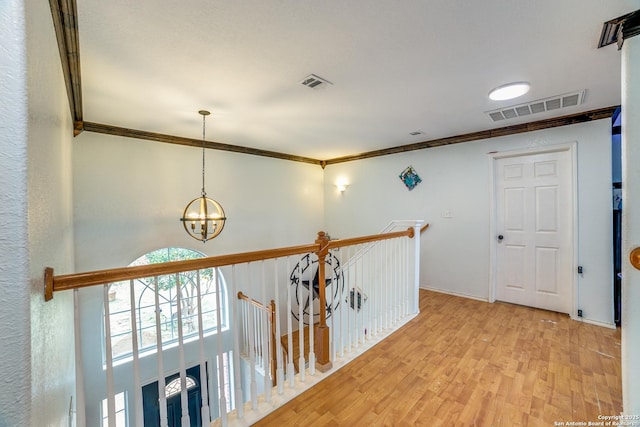 hallway featuring a chandelier, light hardwood / wood-style flooring, and ornamental molding