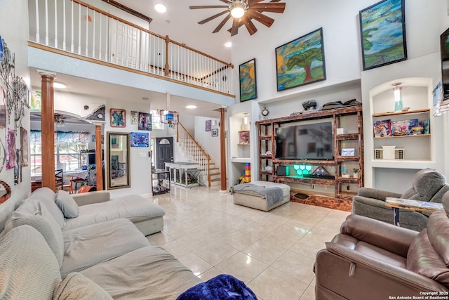 living room featuring built in shelves, ceiling fan, a high ceiling, decorative columns, and light tile patterned floors