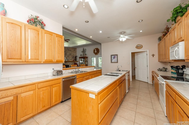 kitchen featuring white appliances, tile counters, a center island with sink, and light tile patterned floors