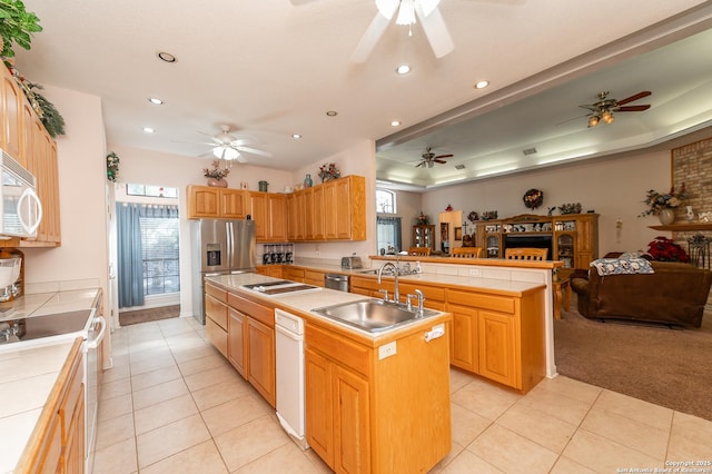 kitchen featuring a kitchen island, tile counters, light colored carpet, kitchen peninsula, and white appliances