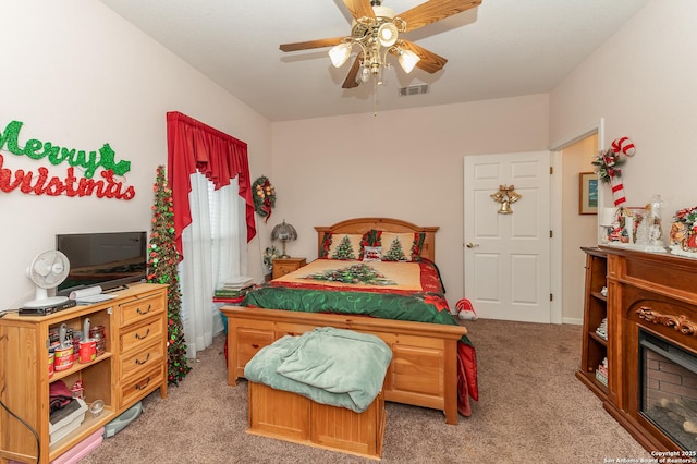 carpeted bedroom with ceiling fan and a fireplace