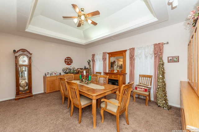 carpeted dining area featuring ceiling fan and a raised ceiling