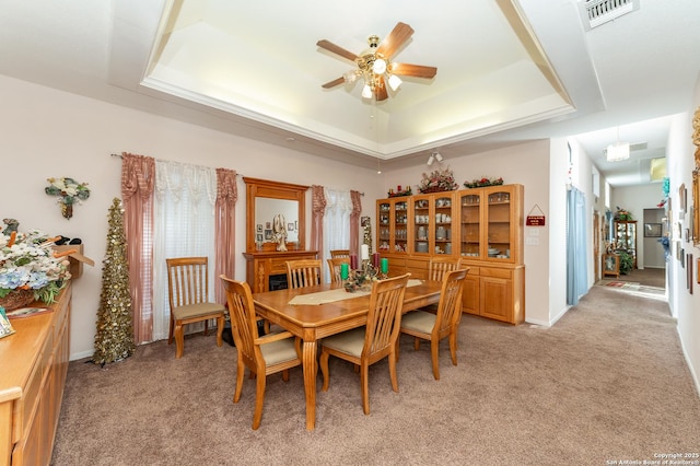 carpeted dining space featuring a tray ceiling and ceiling fan