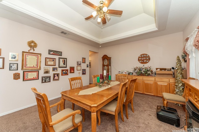 dining room with light carpet, a raised ceiling, and ceiling fan