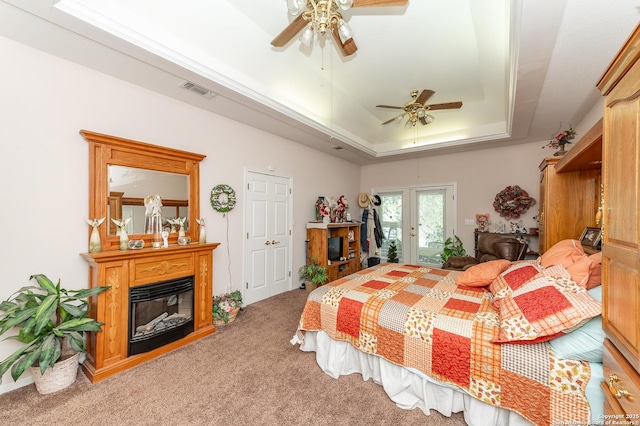 carpeted bedroom featuring a raised ceiling, access to exterior, and ceiling fan