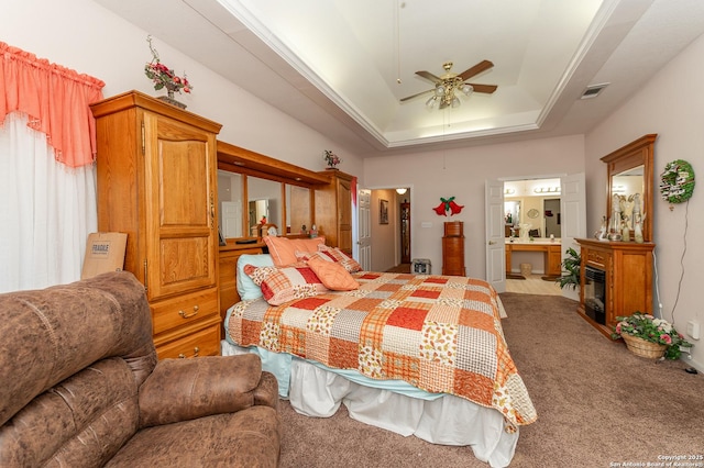 carpeted bedroom with ensuite bathroom, crown molding, ceiling fan, and a tray ceiling