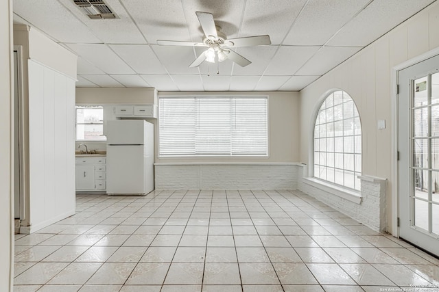 tiled empty room featuring a drop ceiling, a healthy amount of sunlight, sink, and ceiling fan