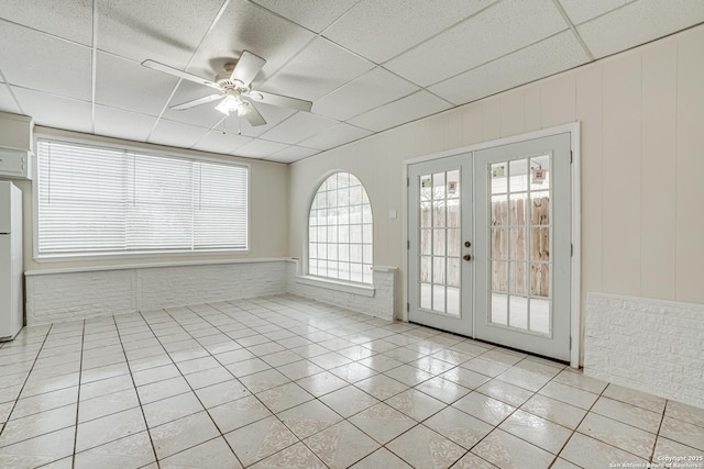 interior space with ceiling fan, french doors, and a drop ceiling