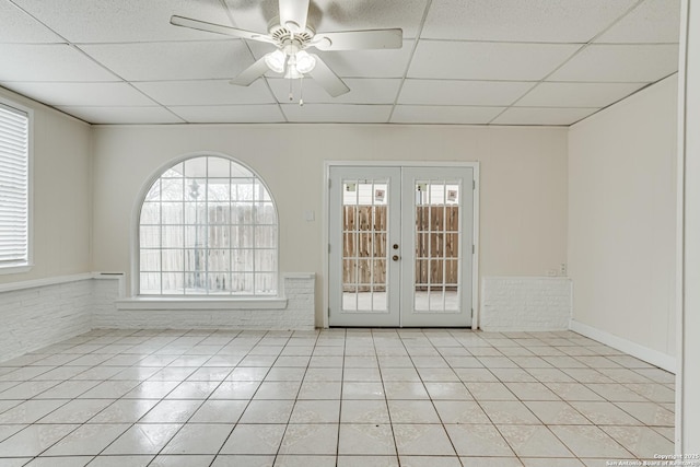 unfurnished room with a wealth of natural light, french doors, light tile patterned floors, and a drop ceiling