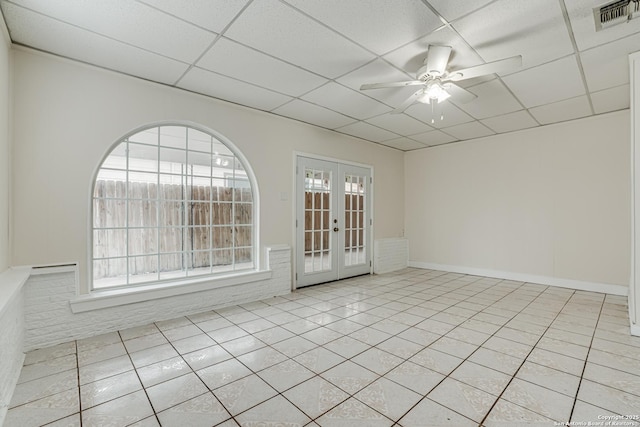 tiled empty room with french doors, a drop ceiling, and ceiling fan