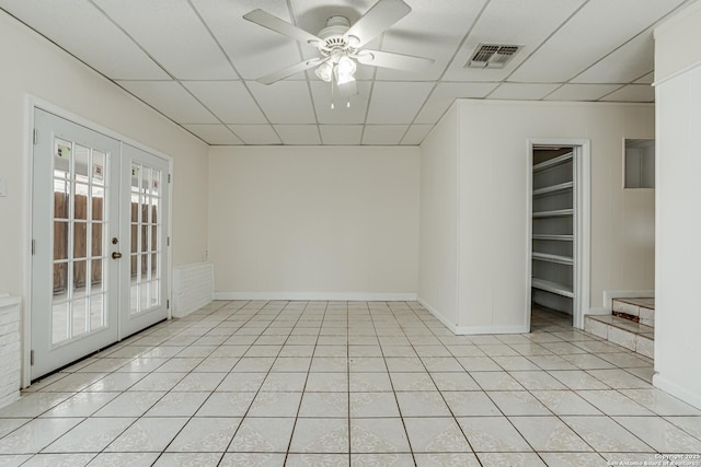 tiled spare room with a drop ceiling, ceiling fan, and french doors