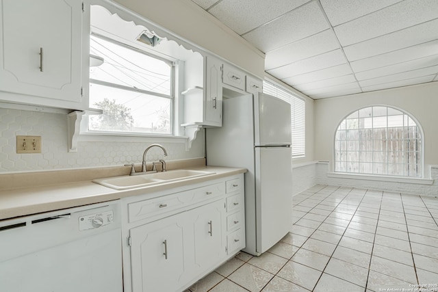 kitchen featuring a drop ceiling, white appliances, white cabinets, sink, and light tile patterned floors