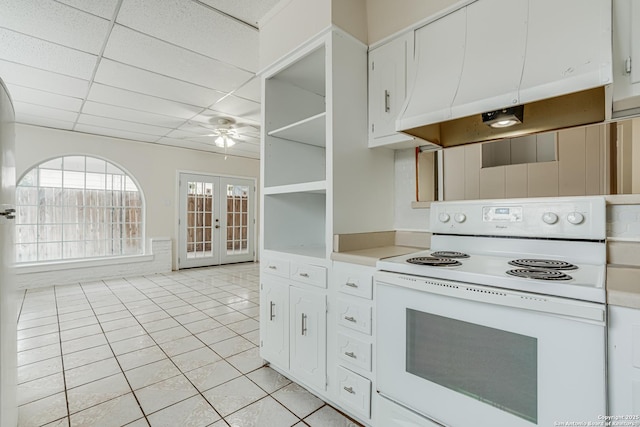 kitchen featuring french doors, range hood, white range with electric stovetop, a paneled ceiling, and white cabinets