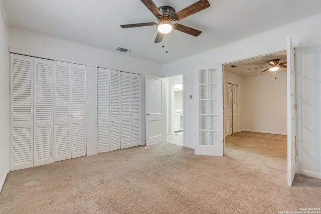 unfurnished bedroom with multiple closets, ceiling fan, french doors, and light carpet