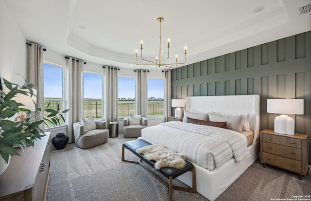 carpeted bedroom with a tray ceiling and an inviting chandelier