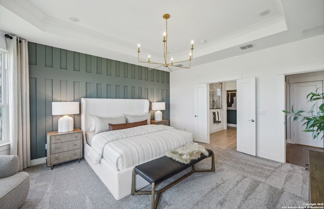 carpeted bedroom featuring a tray ceiling and a chandelier