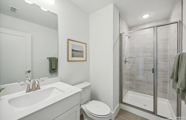 bathroom featuring tile patterned flooring, vanity, toilet, and a shower with door