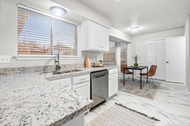 kitchen featuring a textured ceiling, white cabinetry, stainless steel dishwasher, and sink