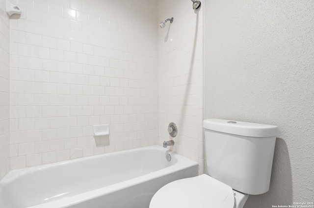 bathroom featuring tiled shower / bath combo and toilet