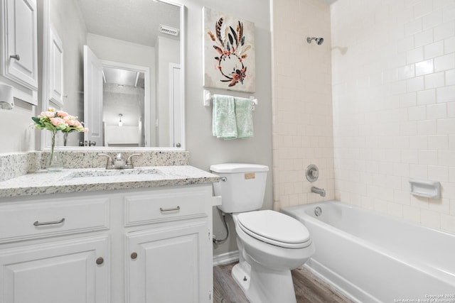 full bathroom with hardwood / wood-style floors, vanity, tiled shower / bath combo, and toilet