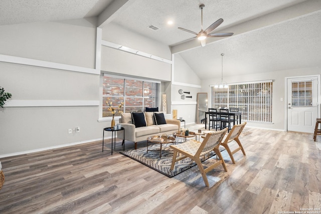 living room with vaulted ceiling with beams, plenty of natural light, wood-type flooring, and ceiling fan with notable chandelier