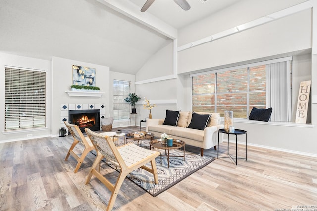 living room featuring ceiling fan, plenty of natural light, light wood-type flooring, and a tile fireplace