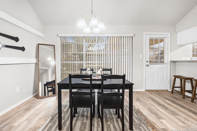 dining area with light hardwood / wood-style flooring, vaulted ceiling, and an inviting chandelier