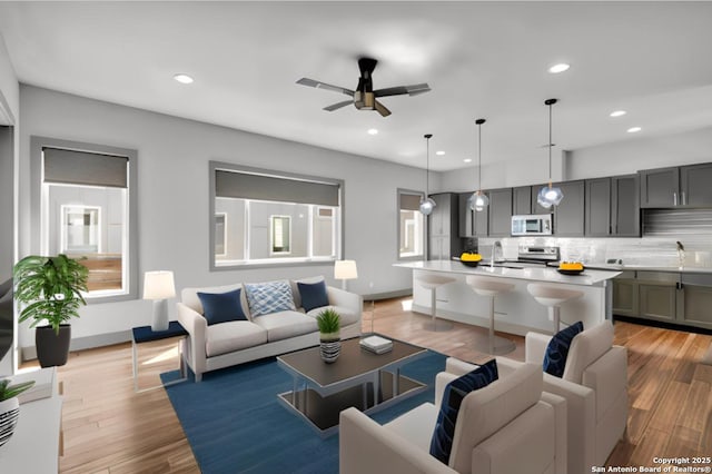 living room with ceiling fan, light hardwood / wood-style floors, and sink